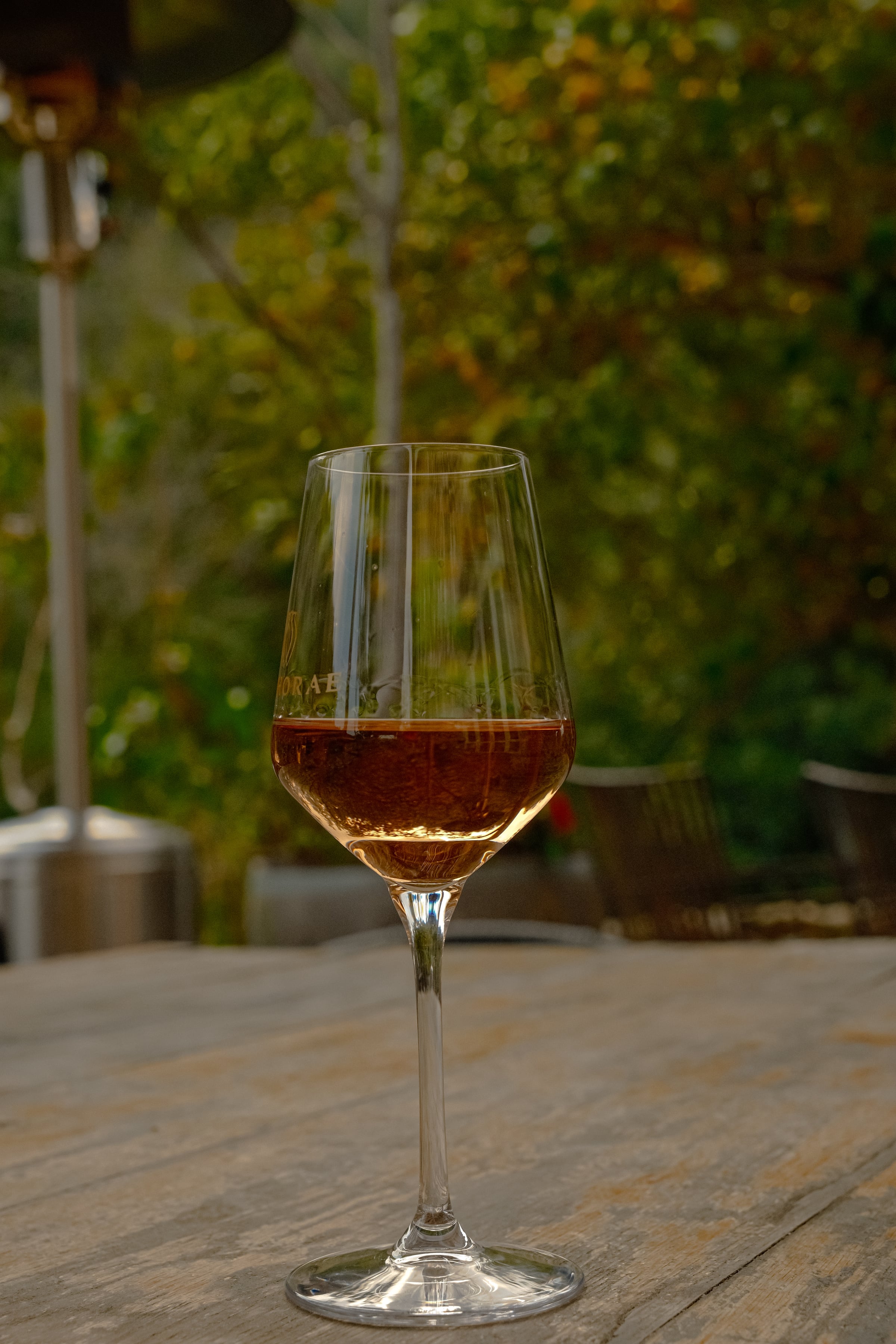 Wine glass with rosé on wooden table, outdoor garden