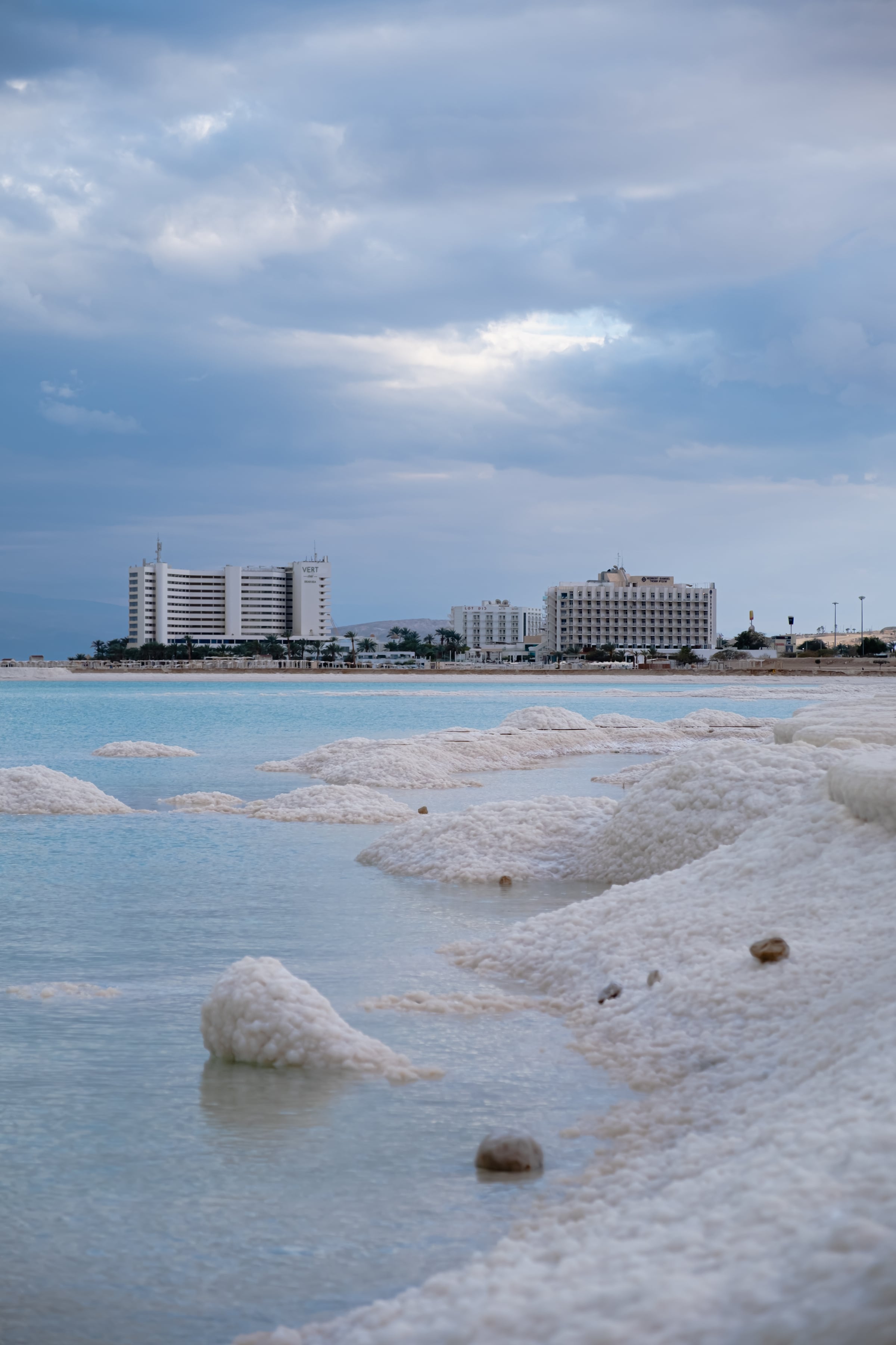 Dead Sea salt formations and turquoise water with hotels in background