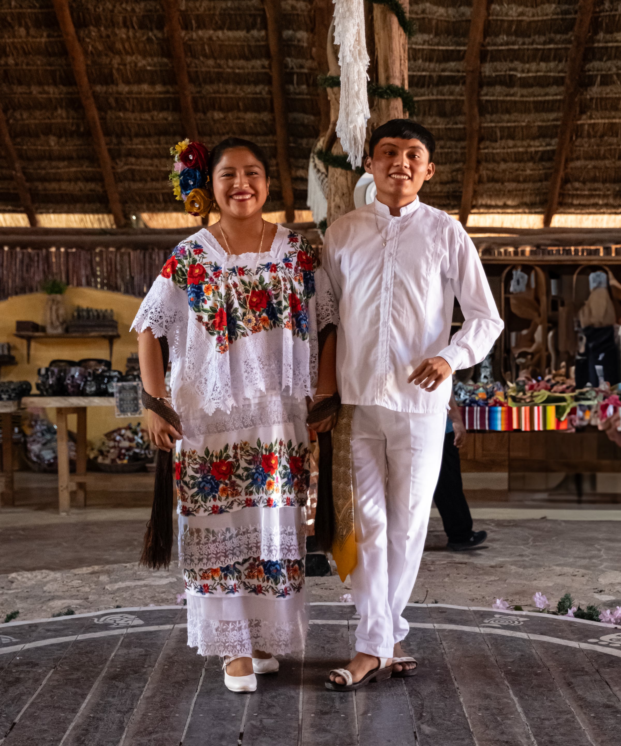 Young couple in traditional Mayan embroidered dress and white guayabera in thatched ceremony hall