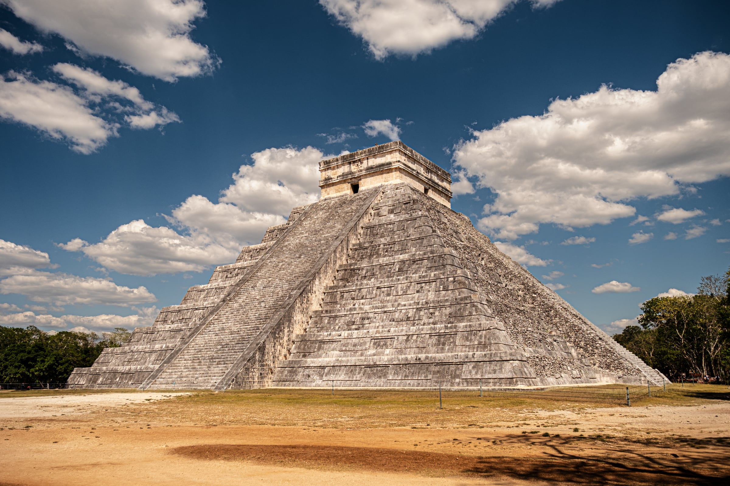 El Castillo pyramid at Chichen Itza under dramatic blue sky with white clouds