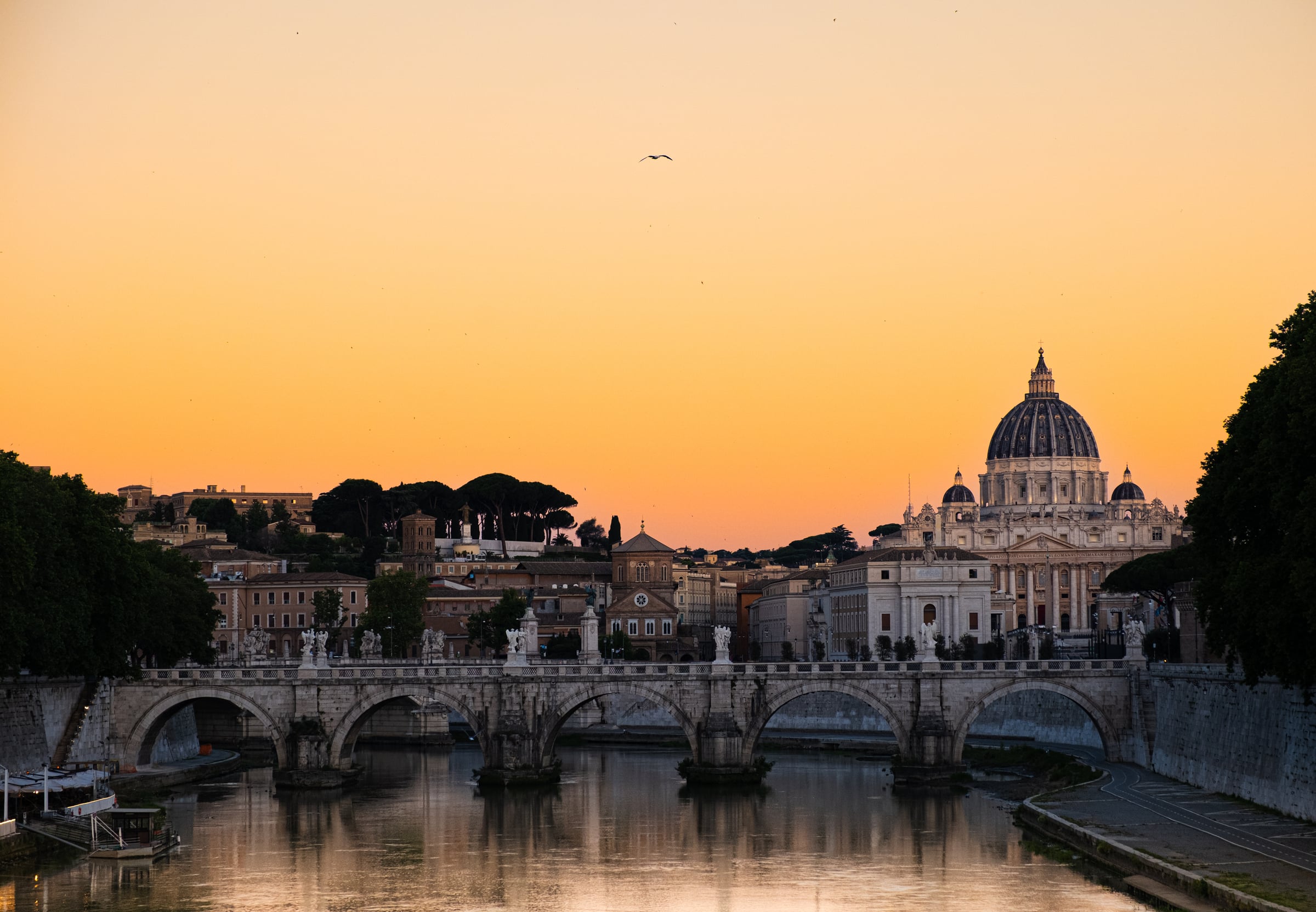 St. Peter's Basilica dome and Ponte Sant'Angelo bridge reflected in the Tiber at sunset